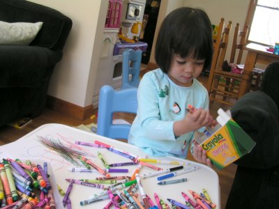 Mia putting her crayons away