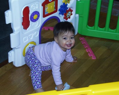 Mia laughing with her shoes in play pen