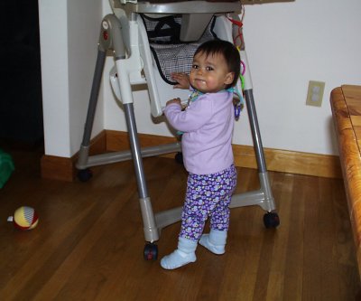 Mia holding herself up with her high chair