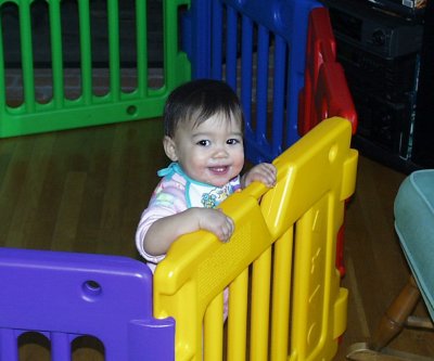 Mia smiling from in her play pen