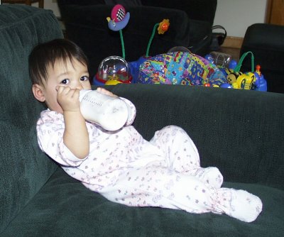 Mia drinking her bottle on the sofa