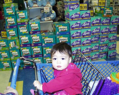 Mia in R' Us, in front of diaper display